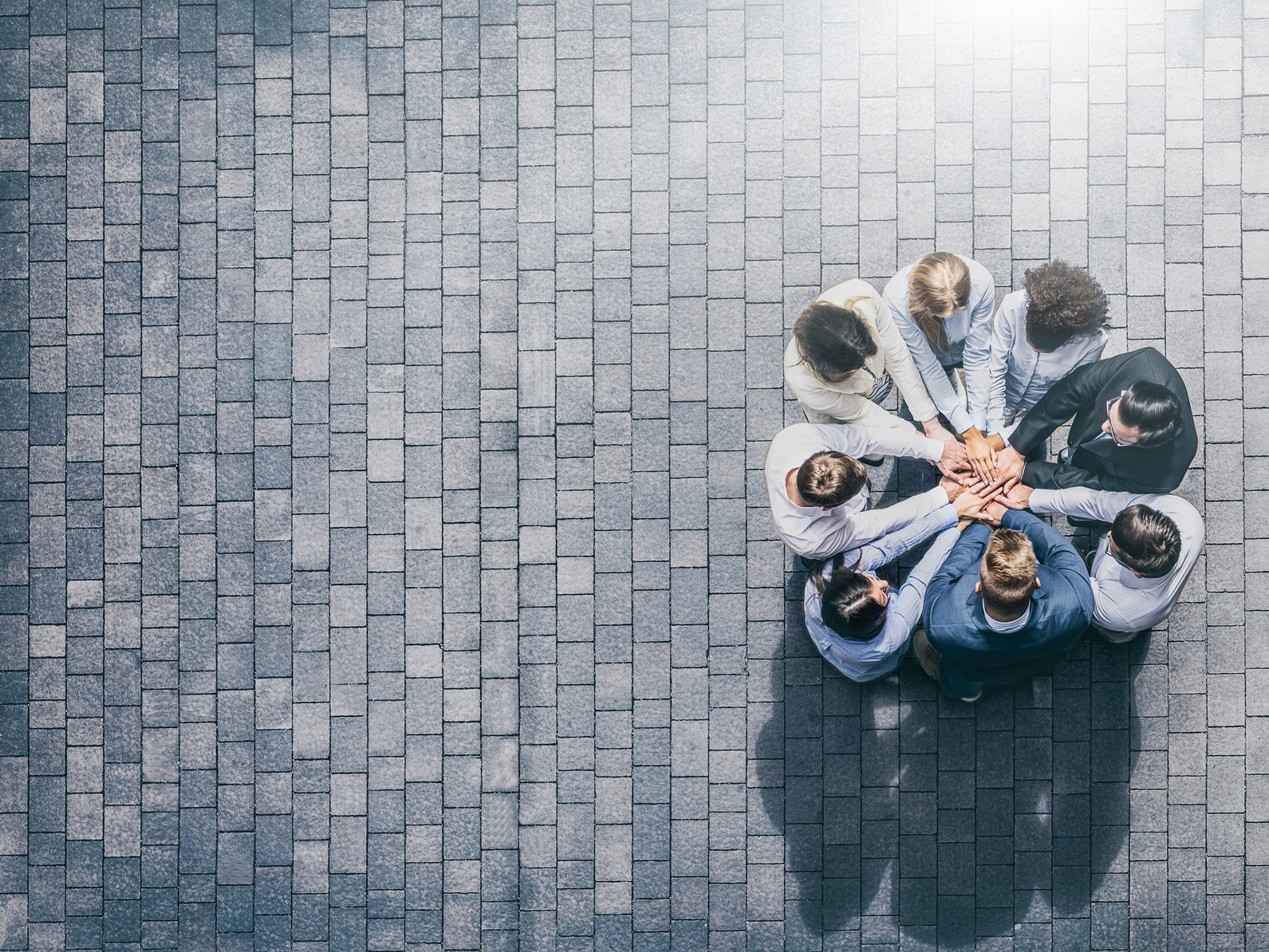 Gruppe mit Händen übereinander, Symbol für Ehrenamt, Teamwork, Beratung und Unterstützung bei ISUV-Themen.