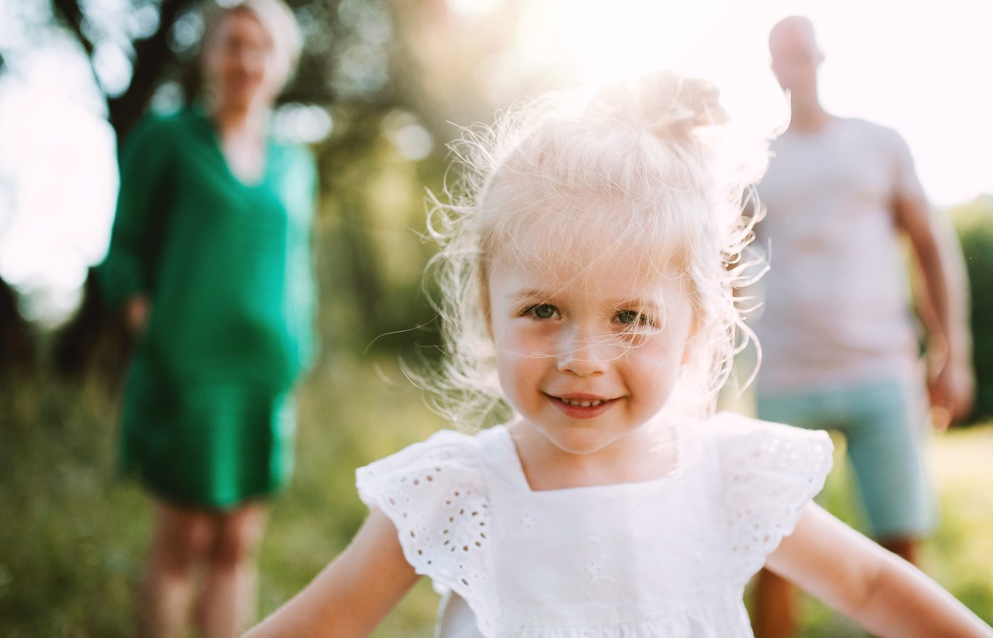 Kind mit Eltern im Hintergrund. Umgangsrecht/Sorgerecht relevant. Familiensituation.
